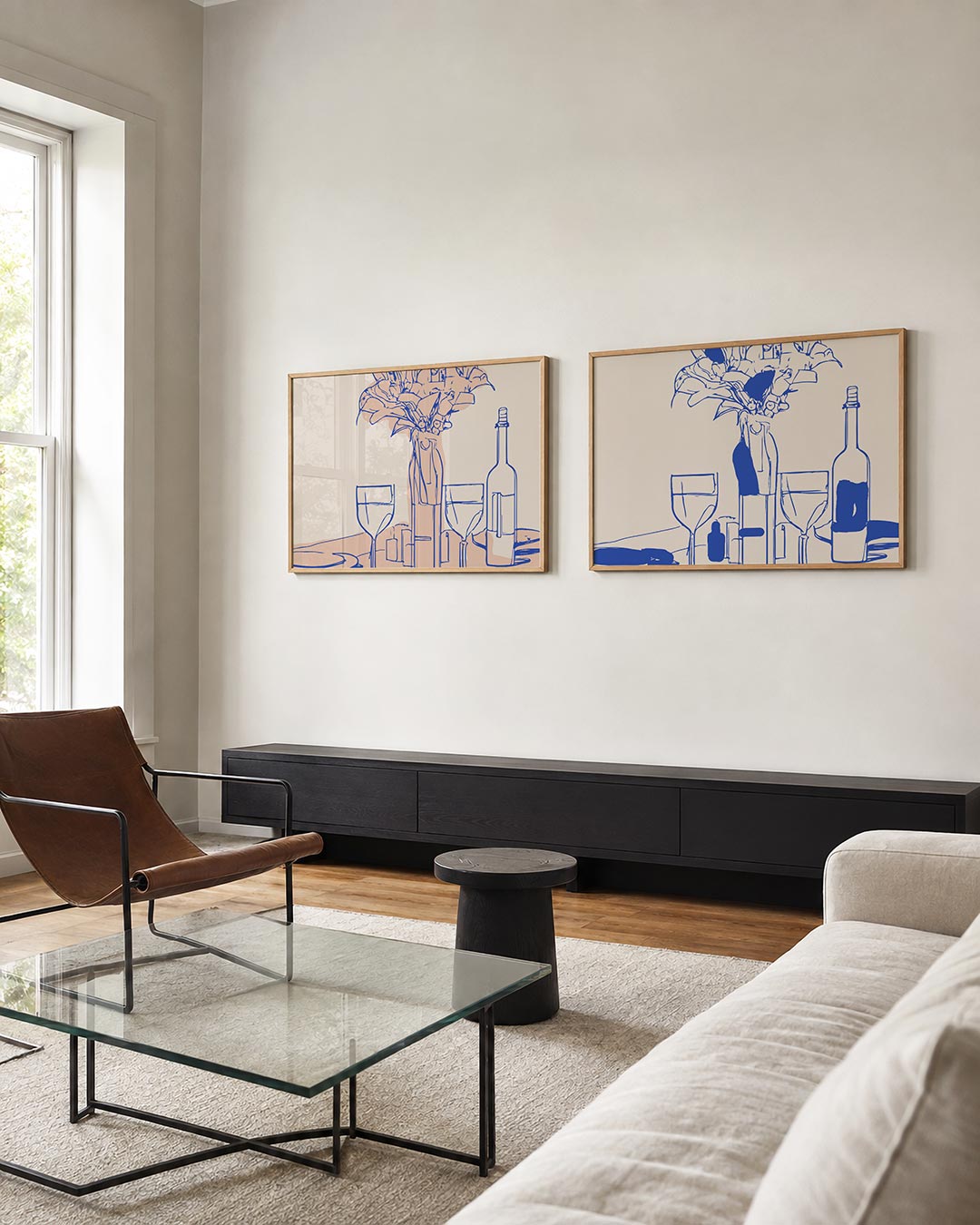 Twee liggende posters met glazen, een fles en bloemen met blauwe contourlijnen, aan de muur in een interieur