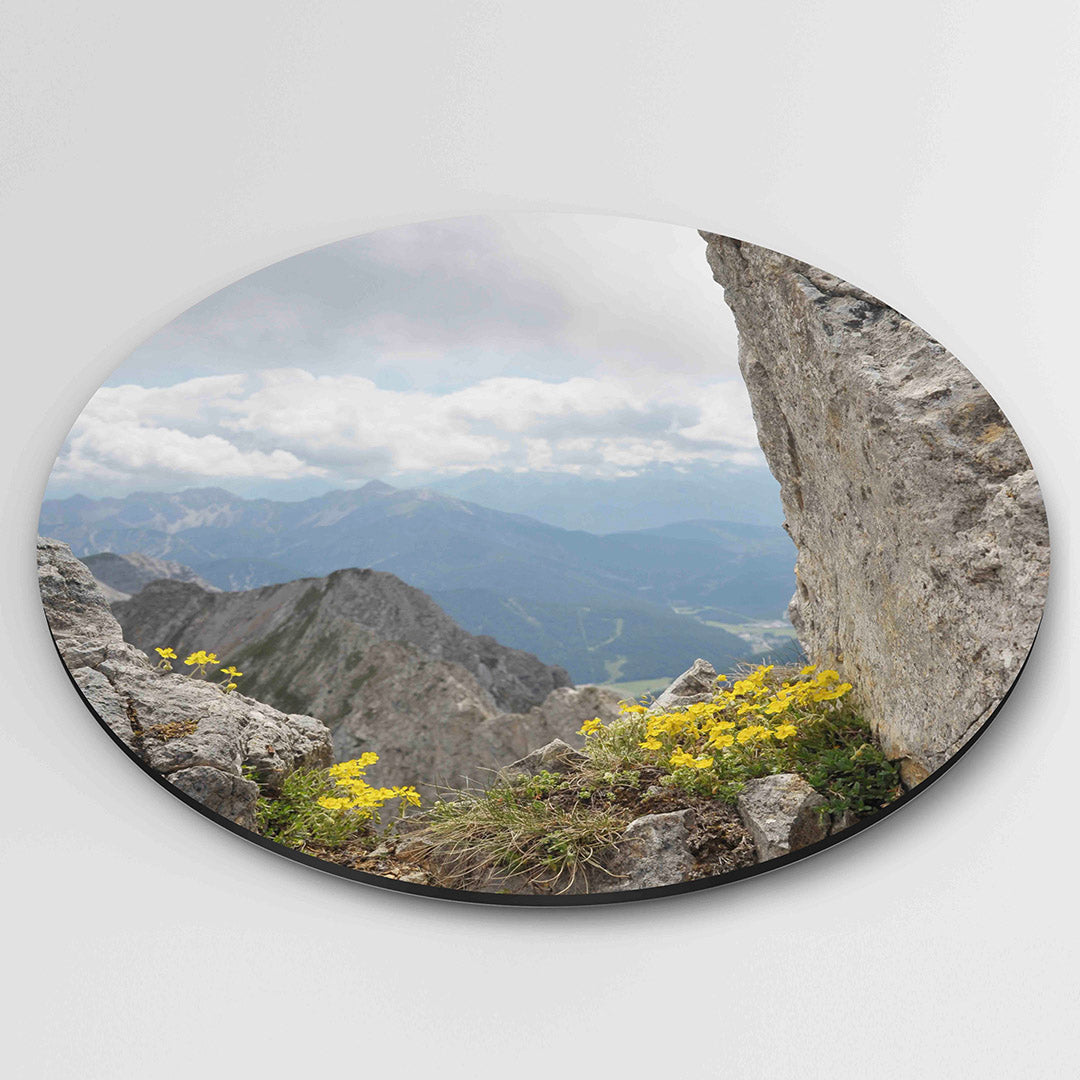 Berglandschap met bloemen – muurcirkel fotografie als moderne wanddecoratie