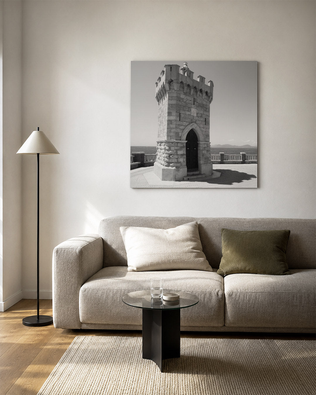 Toren kunstwerk – vierkante wanddecoratie – een stenen toren met kantelen staat op een terras met uitzicht op de zee. De