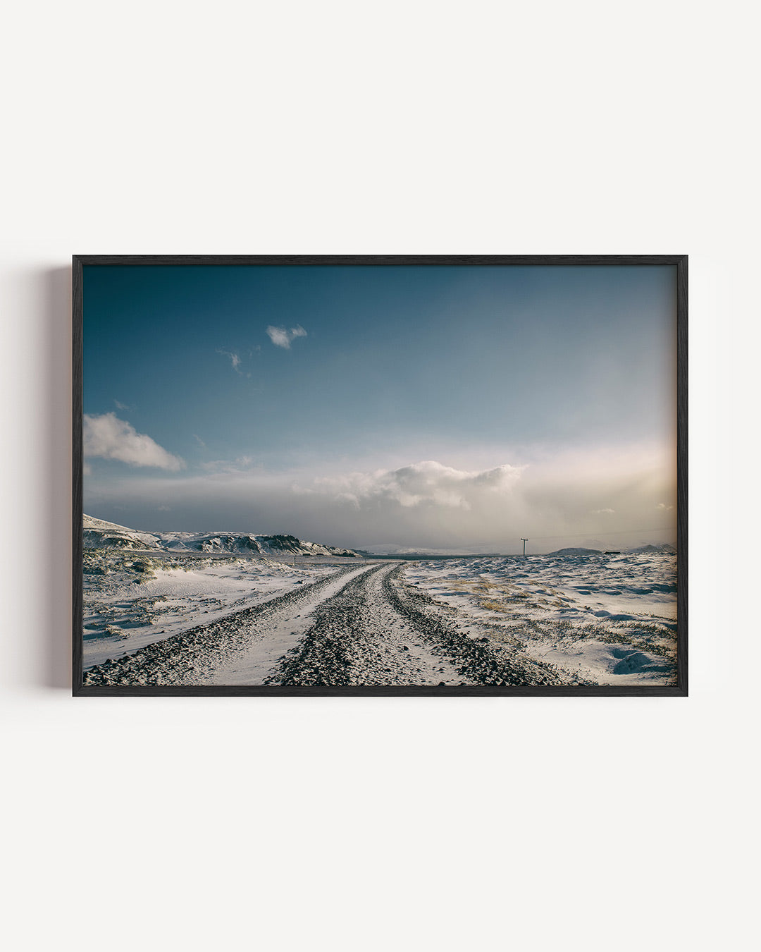 Winterse landschap poster – liggende wanddecoratie – een uitgestrekt winterlandschap met een kronkelende weg. De lucht is