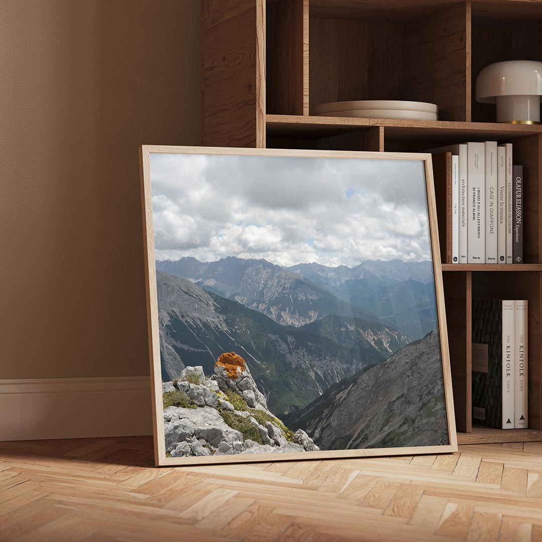 Berglandschap met wolken poster – detailweergave – een berglandschap met wolkenluchten en een rots met oranje mos op de