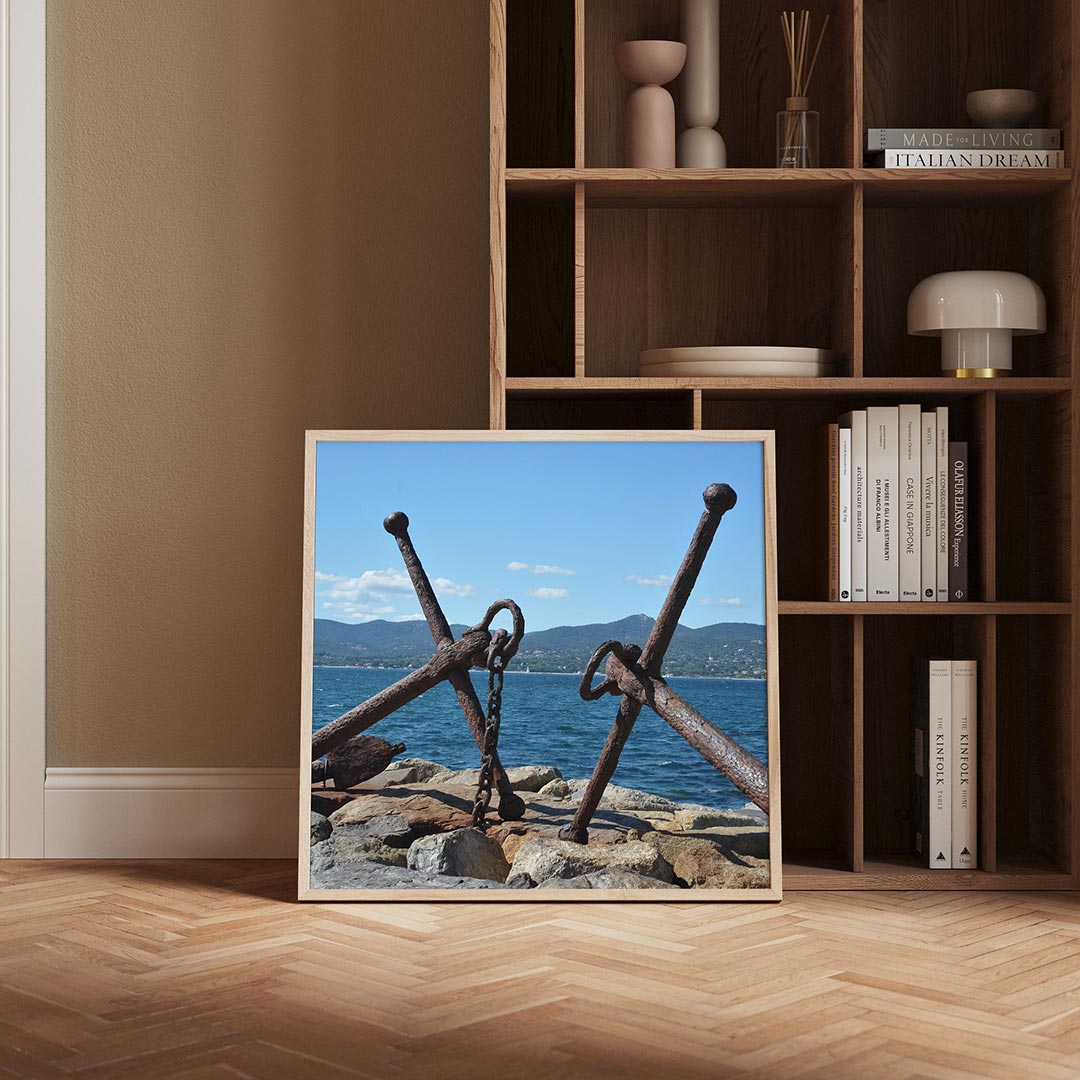Ankers aan zee poster – derde productweergave – twee verweerde ankers liggen op rotsen aan de kust, met een helderblauwe
