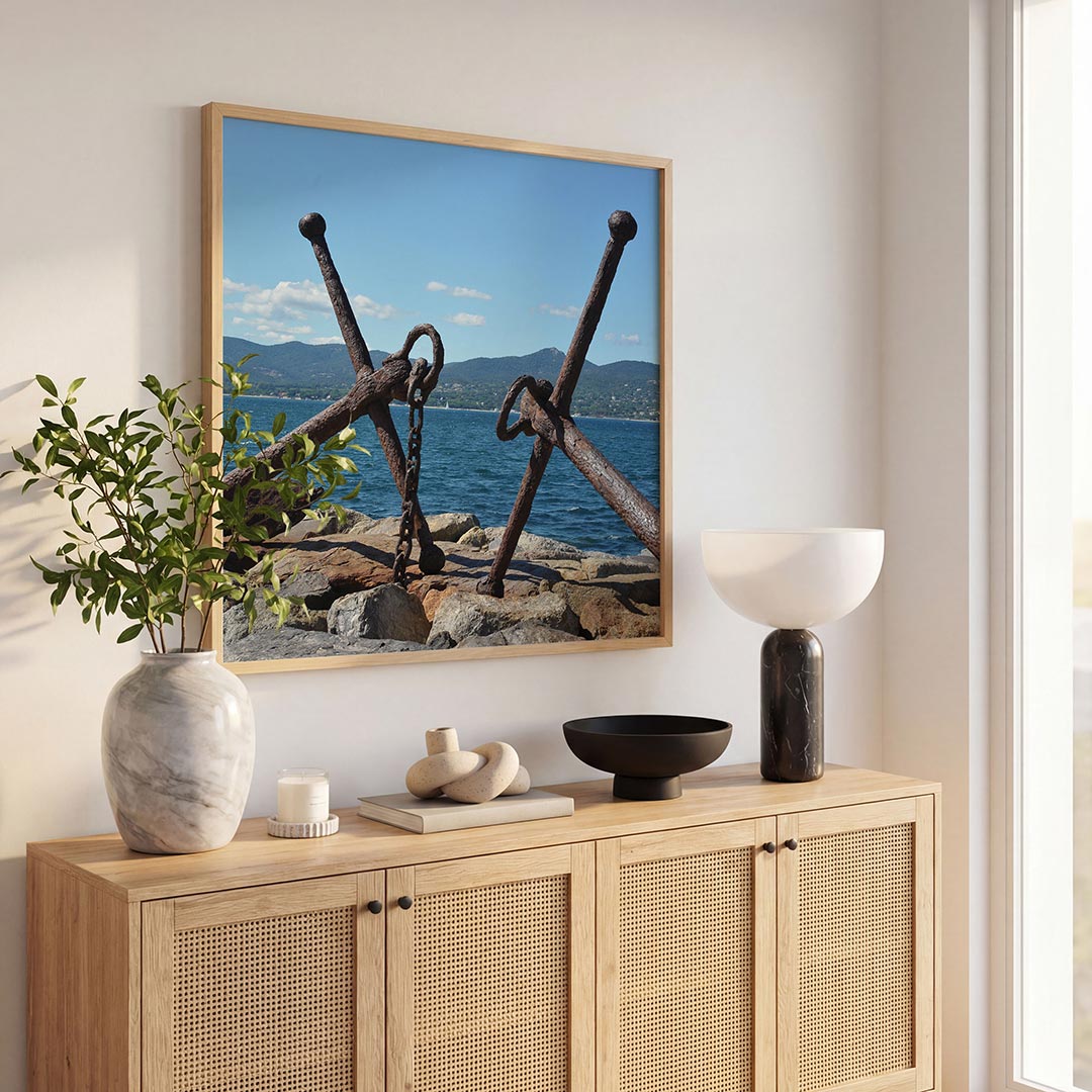 Ankers aan zee poster – tweede productweergave – twee verweerde ankers liggen op rotsen aan de kust, met een helderblauwe