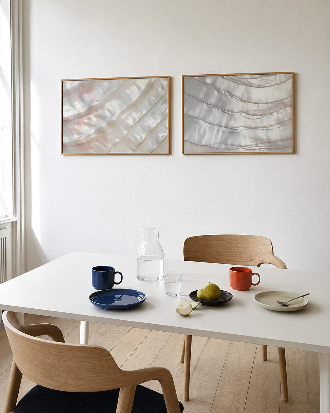 Tweedelige posterset met een spel van glanzende, golvende lijnen in zachte parelmoertinten, getoond in een interieur
