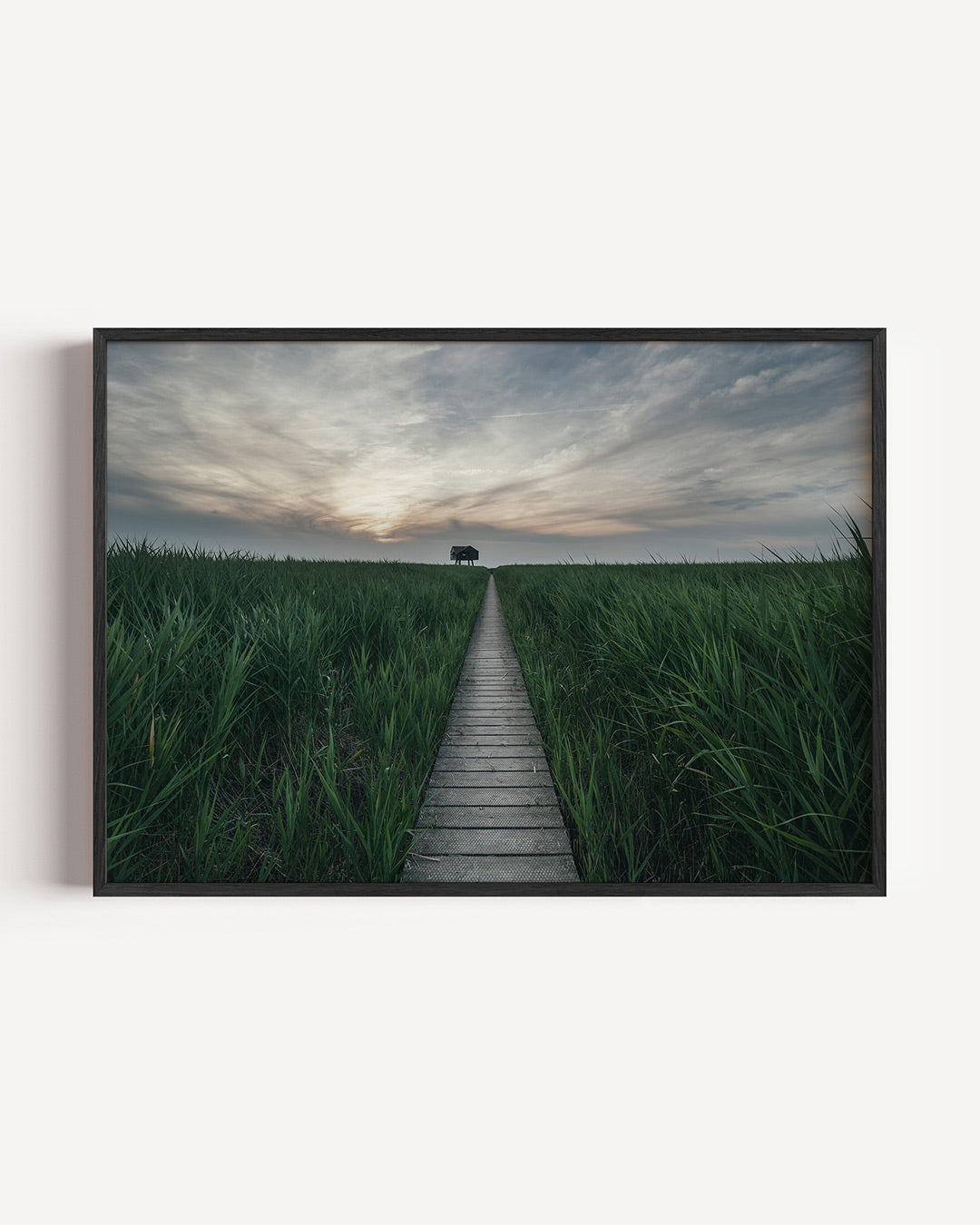 Rustige landschapspad poster – liggende wanddecoratie – een houten pad leidt door groene velden naar een silhouet van een