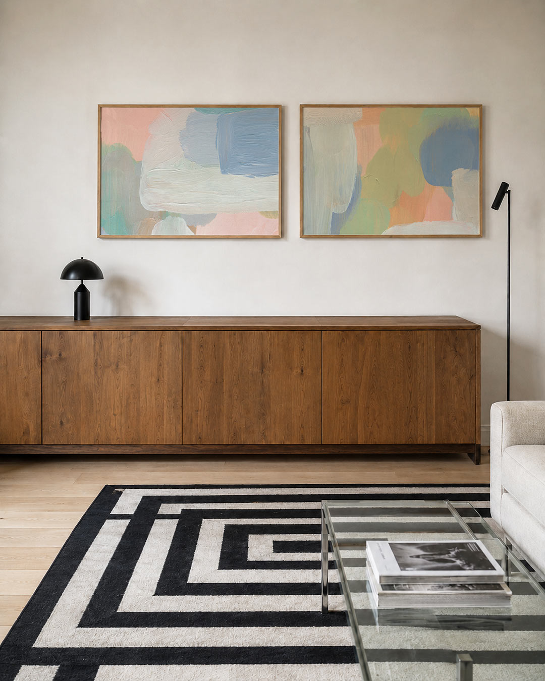 Twee liggende posters met vloeiende penseelstreken in pastelkleuren, aan de muur in een interieur