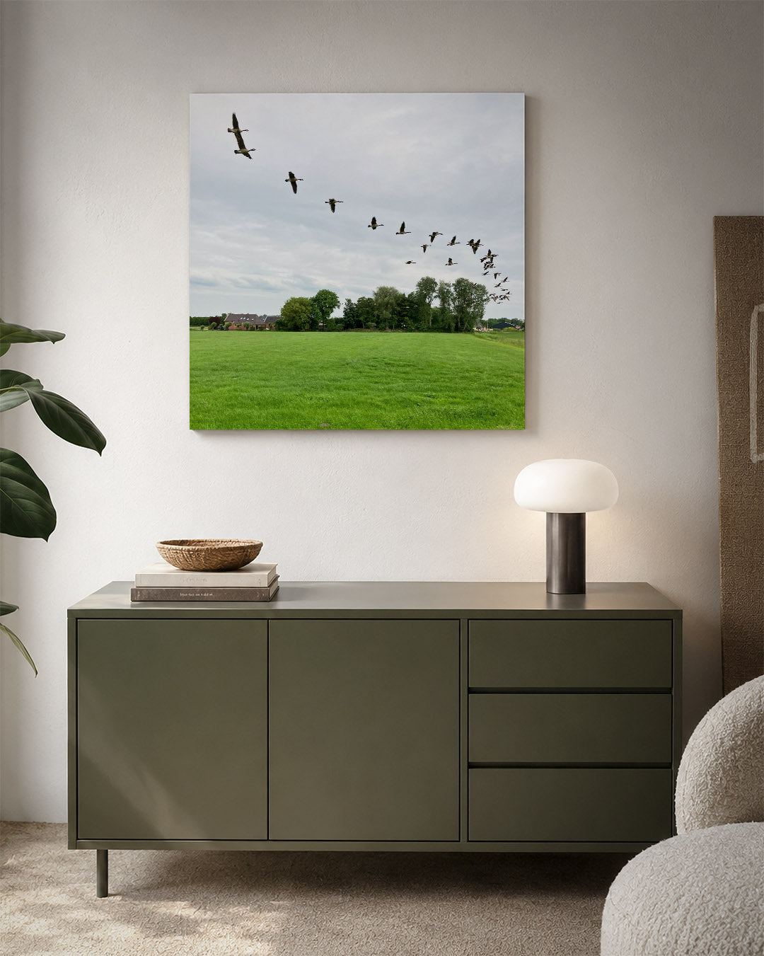 Vliegende vogels kunstwerk – detailweergave – een groep vogels vliegt in formatie over een groen veld met bomen en een huis
