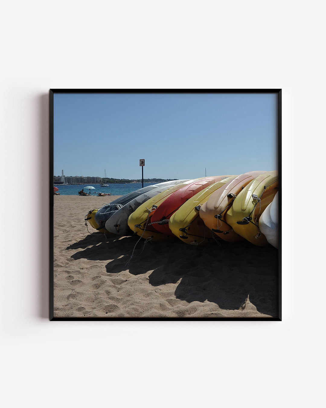Kleurrijke kajaks op strand poster – vierkante wanddecoratie – een rij felgekleurde kajaks ligt op een zonnig strand, met een