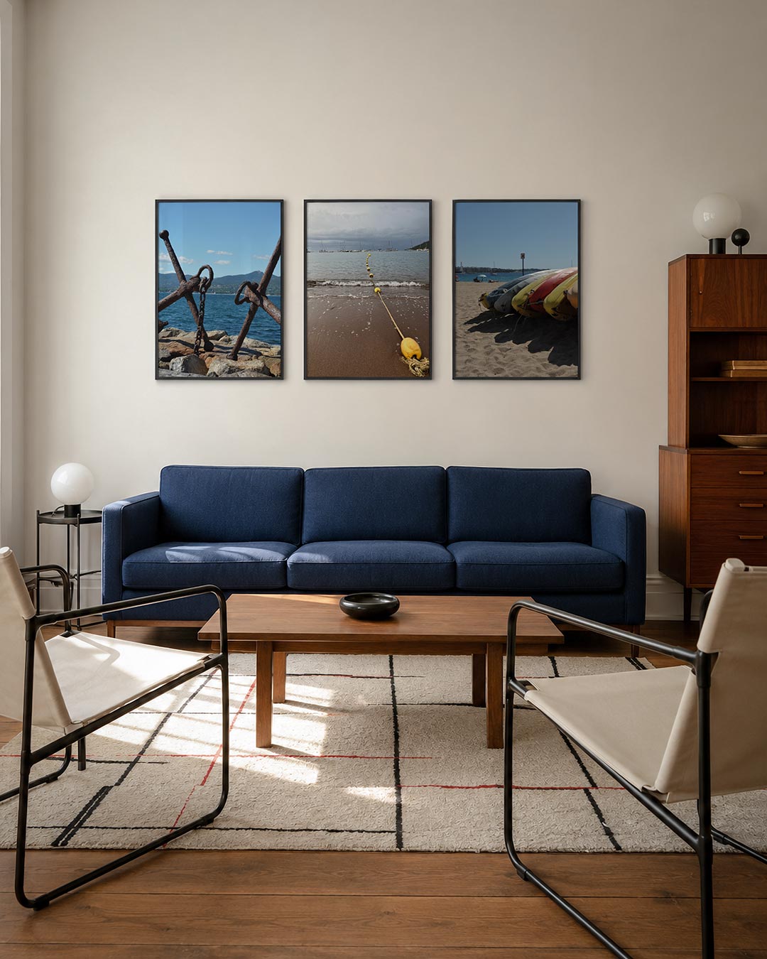 Anker en zee driedelige posterset – roestige ankers rusten op rotsen met een blauwe zee en groene heuvels op de achtergrond.