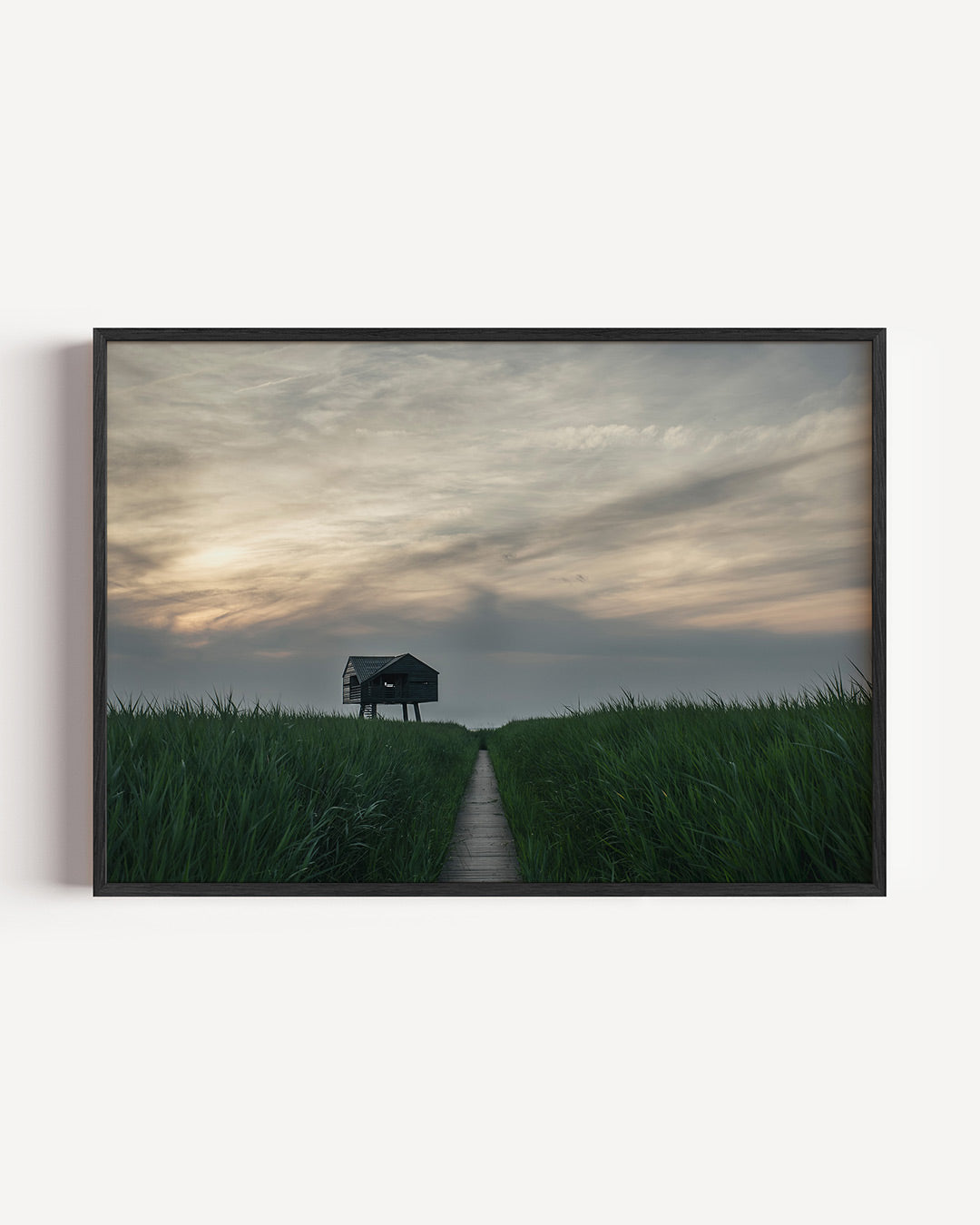 Hut in het veld poster – liggende wanddecoratie – een houten hut staat in een uitgestrekt groen veld onder een bewolkte