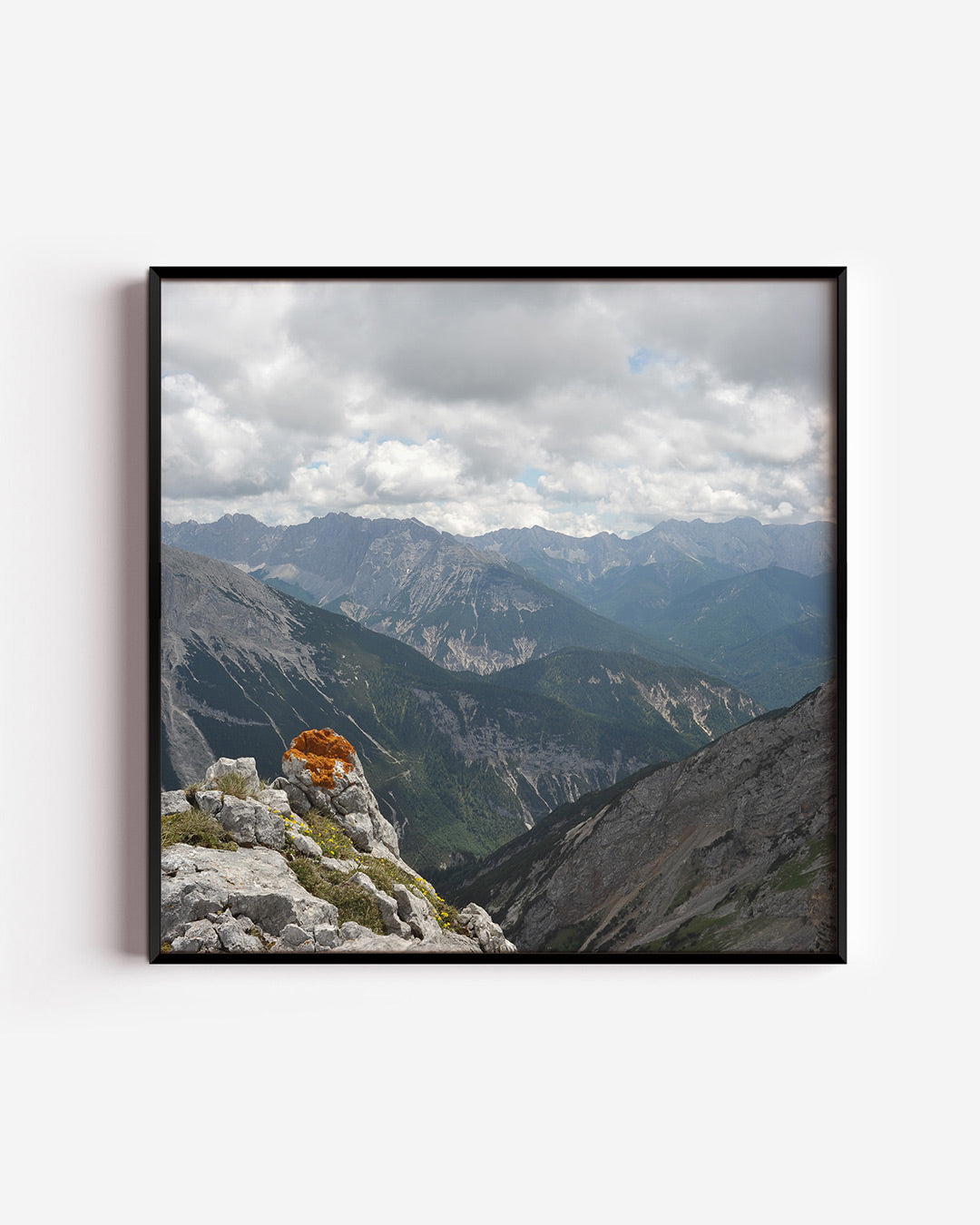 Berglandschap met wolken poster – vierkante wanddecoratie – een berglandschap met wolkenluchten en een rots met oranje mos op