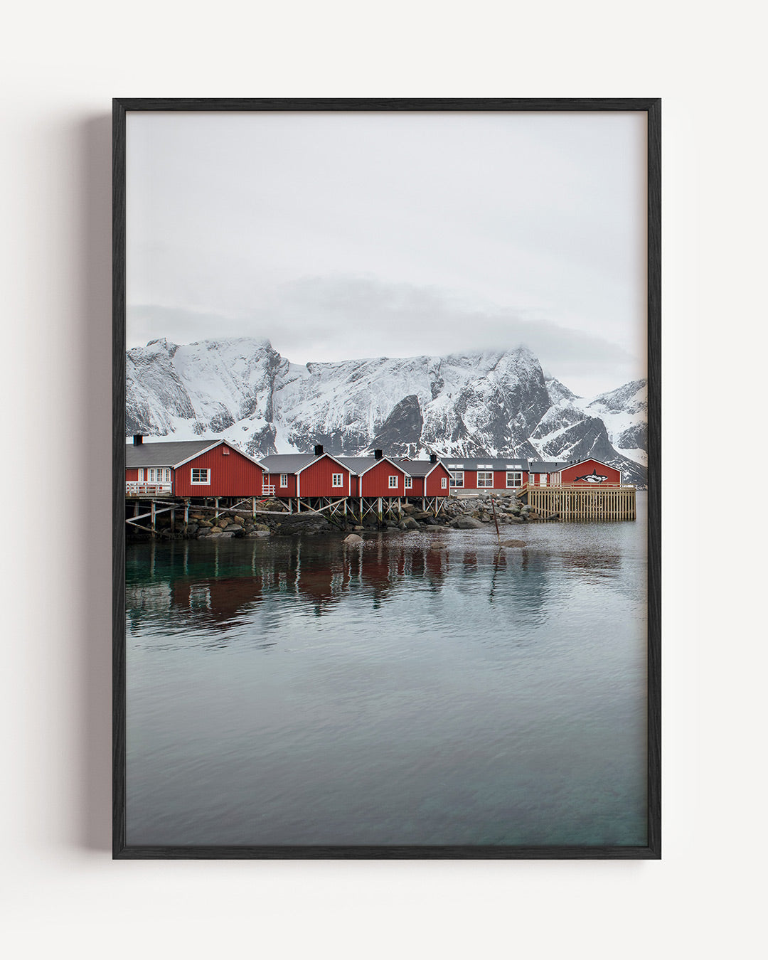 Rode huisjes bergen poster – portret wanddecoratie – deze poster toont rode huisjes op palen aan het water met besneeuwde