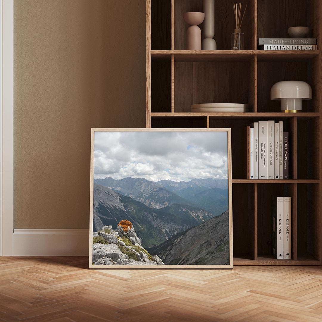 Berglandschap met wolken poster – derde productweergave – een berglandschap met wolkenluchten en een rots met oranje mos op
